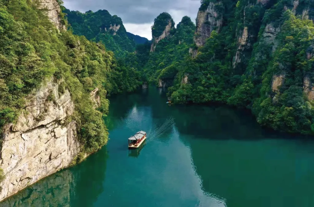 Boat travelling through the green mountain scenery of Baofeng Lake in Zhangjiajie