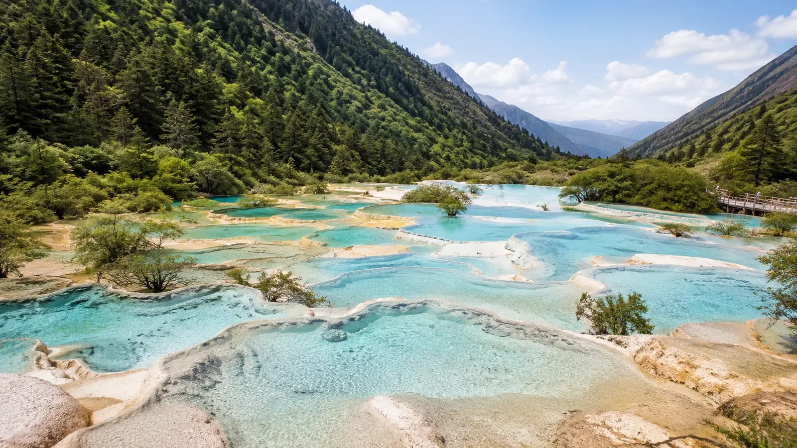 Natural turquoise travertine pools and forested slopes in Huanglong Scenic Area, Sichuan